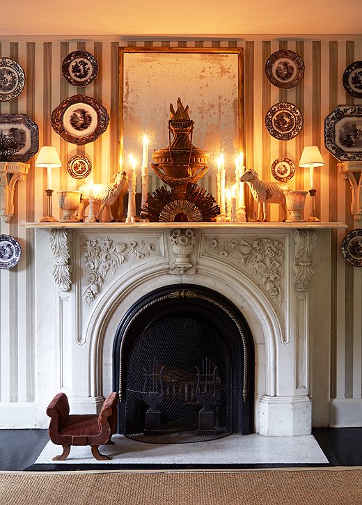 Striped walls, symmetrical arrangements of antique transferware on the wall and decor on the mantel, and a fireplace surround with carved flowers and foliage: This vignette is the ultimate in Regency chic. Room by Dransfield and Ross. Photo by Manuel Rodriguez.
